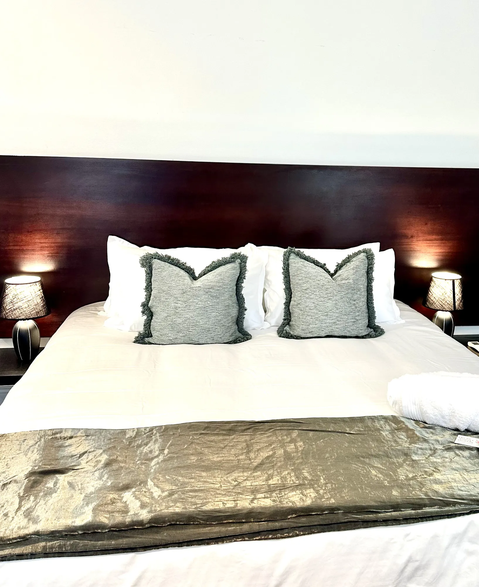 A dark timber headboard and grey cushions in a Casa Dias bedroom