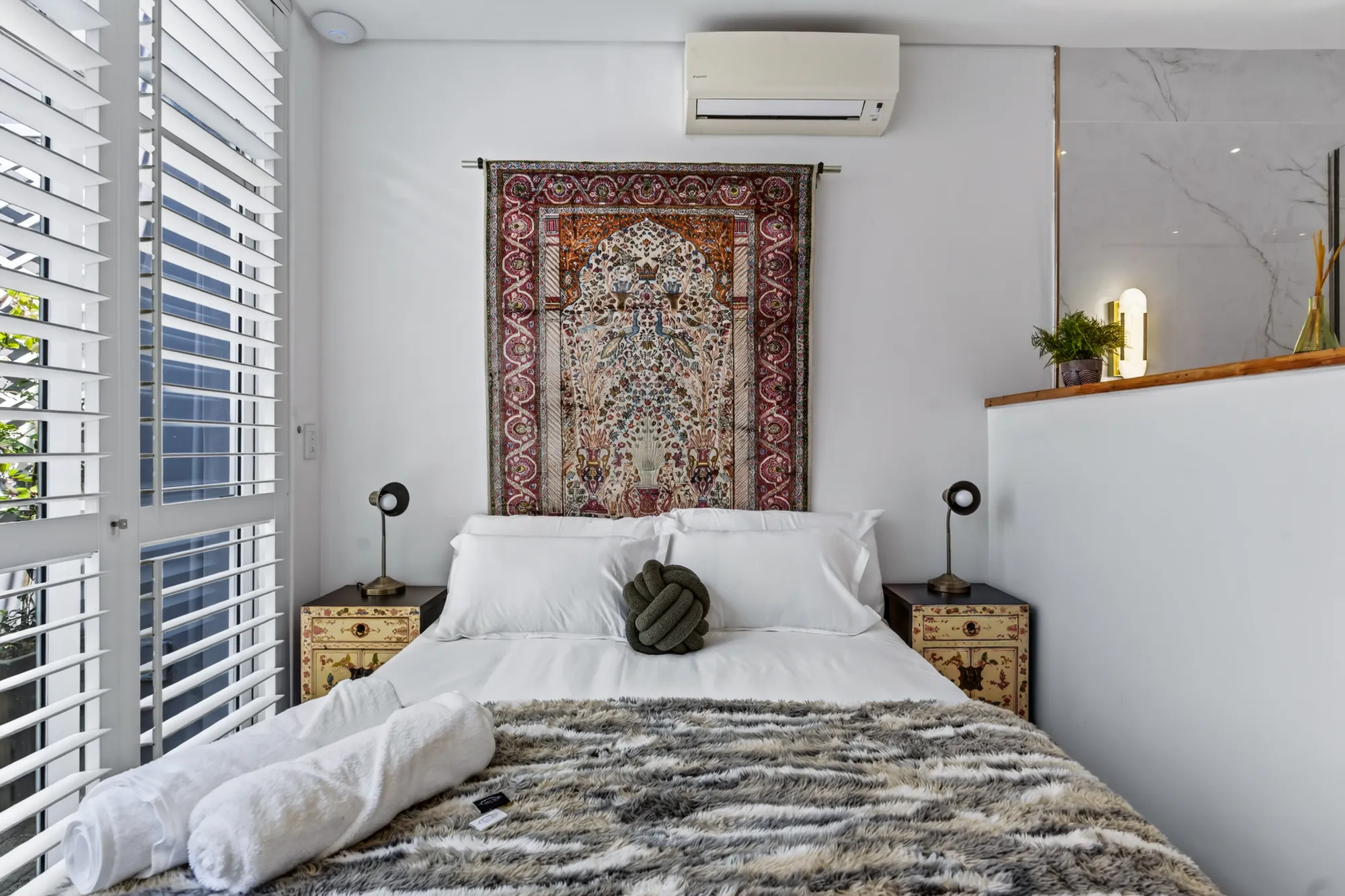 A made bed with a tapestry headboard in a Casa Dias courtyard bedroom